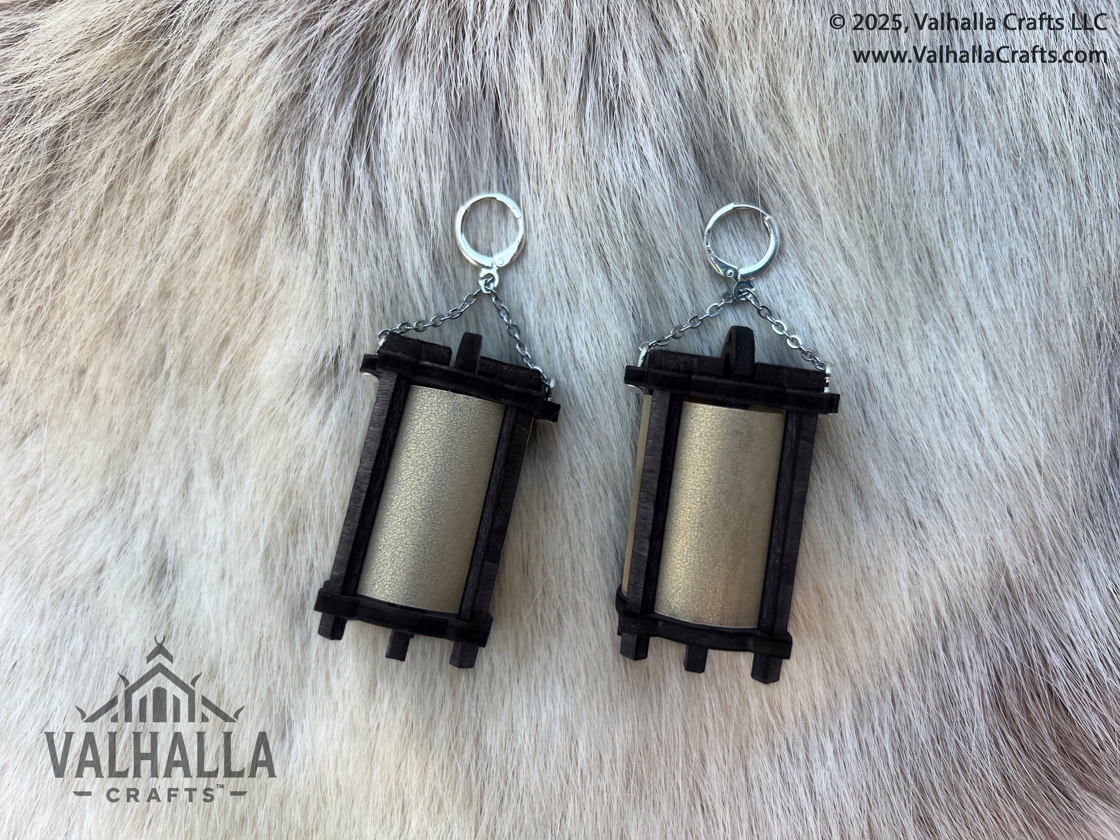 Two black wooden lantern earrings with silver metal lay on a white fur backdrop. Copyright 2025 Valhalla Crafts LLC www.ValhallaCrafts.com